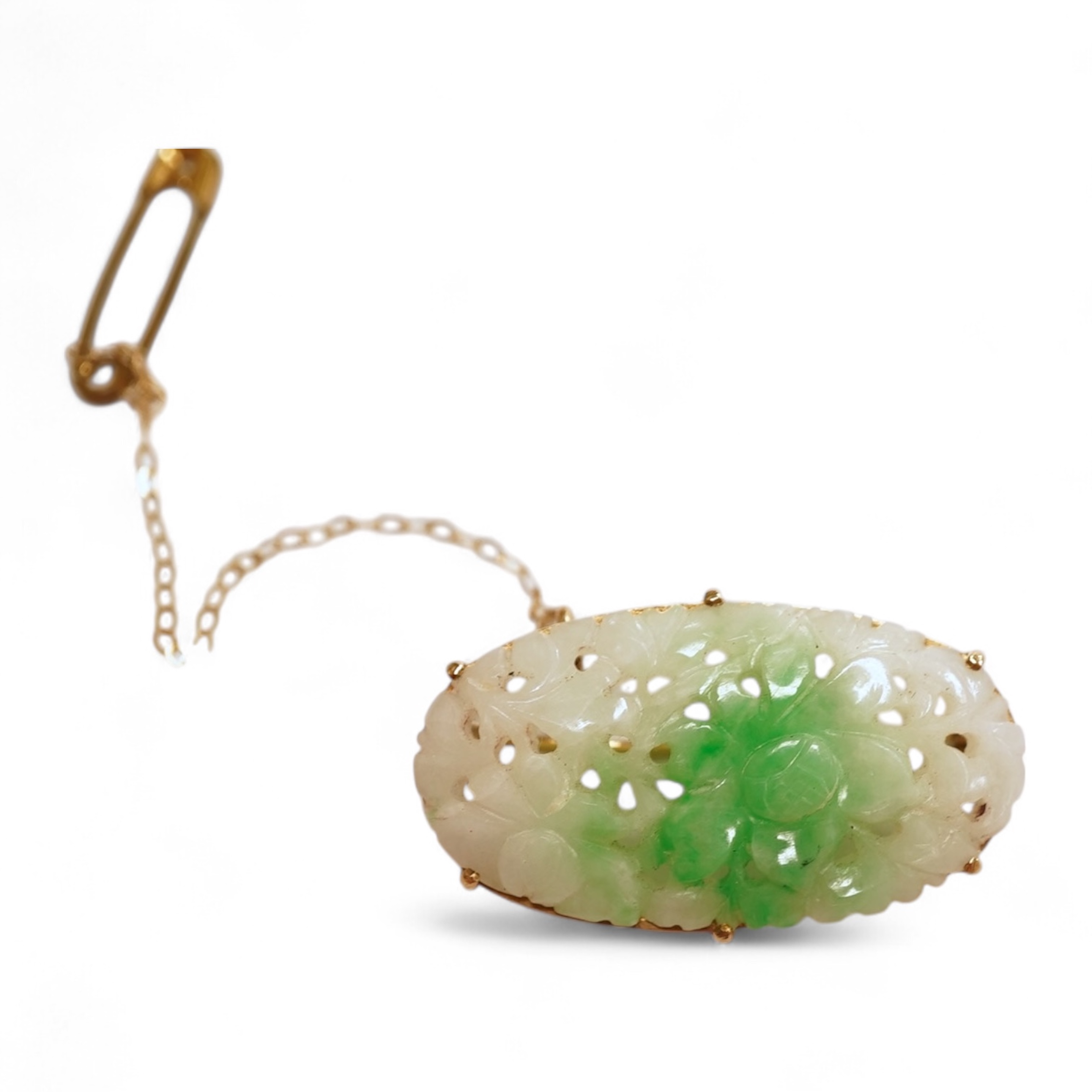 A jadeite brooch, set with an oval jadeite of mottled green and white, carved to depict flowers, mounted in 9ct gold, length 3.2cm, British hallmarks, maker's mark for Cropp & Farr, gross weight approximately 4.5 grams,